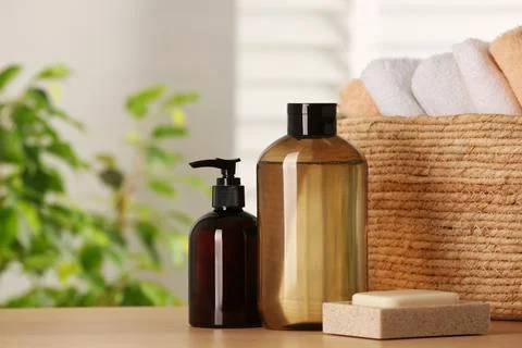 Solid shampoo bar and bottles of cosmetic product on wooden table in bathroom 스톡 사진