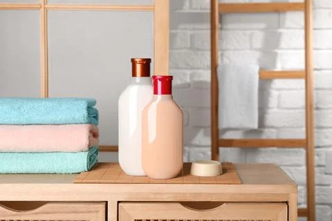 Solid shampoo bar and bottles of cosmetic product on wooden table in bathroom 스톡 사진