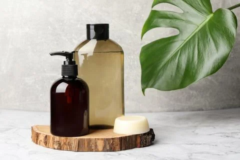 Solid shampoo bar and bottles of cosmetic product on white marble table, sp.. 스톡 사진
