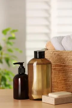 Solid shampoo bar and bottles of cosmetic product on wooden table in bathroom Stock Photos