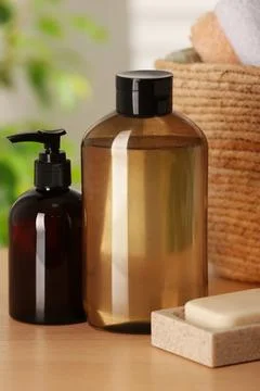 Solid shampoo bar and bottles of cosmetic product on wooden table in bathro.. 스톡 사진