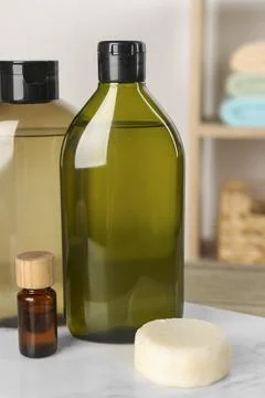 Solid shampoo bar and bottles of cosmetic product on wooden table in bathro.. Stock Photos