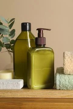 Solid shampoo bar and bottles of cosmetic product on wooden table near beig.. Stock Photos