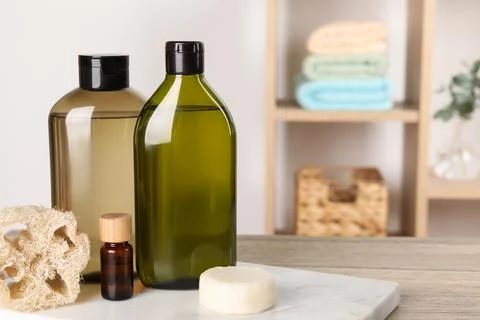 Solid shampoo bar and bottles of cosmetic product on wooden table in bathro.. Stock Photos