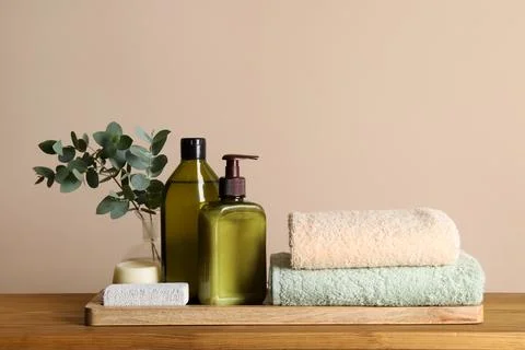 Solid shampoo bar and bottles of cosmetic product on wooden table near beig.. Stockfoto's