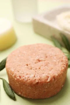 Solid shampoo bar and leaf on green background, closeup. Hair care Foto stock