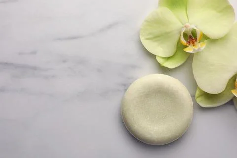 Solid shampoo bar and orchid flowers on white marble table, flat lay with s.. 스톡 사진