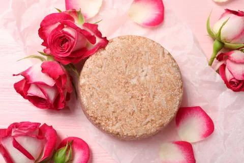 Solid shampoo bar and roses on pink wooden table, flat lay. Hair care 写真素材