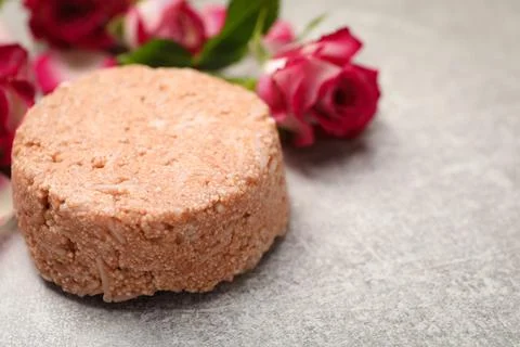 Solid shampoo bar and roses on light grey table, closeup. Space for text Stock Photos