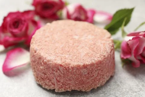 Solid shampoo bar and roses on light grey table, closeup. Hair care Foto stock