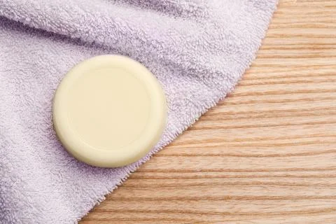Solid shampoo bar and towel on wooden table, top view. Space for text Stock Photos
