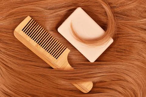 Solid shampoo bar and wooden comb on red hair Concept for eco friendly healthy 写真素材