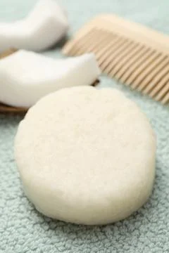 Solid shampoo bar, comb and coconut on light blue cloth, closeup Stockfoto's