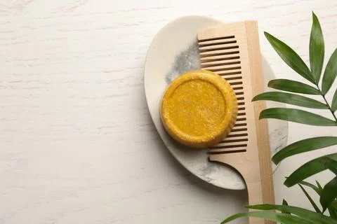 Solid shampoo bar, hair comb and green branch on white wooden table, top vi.. Stock Photos