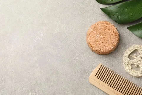 Solid shampoo bar, monstera leaf, comb and loofah on grey table, flat lay. Sp 写真素材