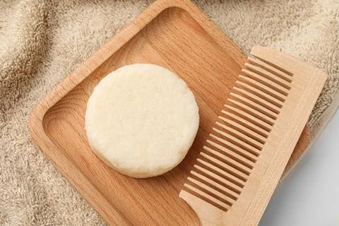 Solid shampoo bar, wooden comb and towel on light table, flat lay 스톡 사진
