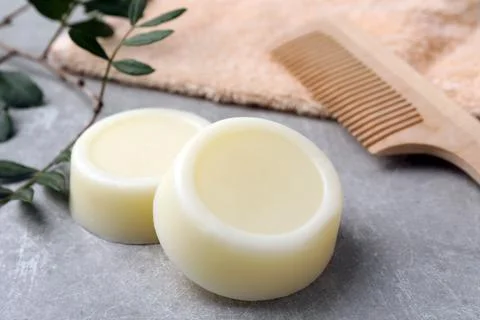 Solid shampoo bars, green twig and comb on grey table 写真素材