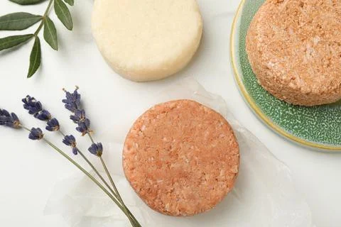 Solid shampoo bars, green twig and lavender on light table, flat lay Stock Photos