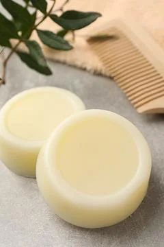 Solid shampoo bars, green twig and comb on grey table Foto stock