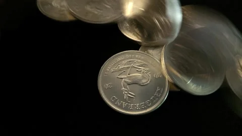 Solid silver coins roll onto a black surface and come to rest in a pile Stock Footage 245370052