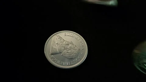Solid silver coins roll onto a black surface and come to rest in a pile Stock Footage 245370056