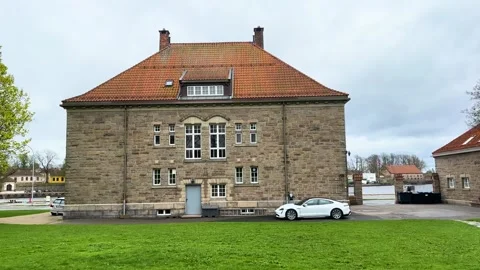 Solid stone historic building orange clay tiled roof stands beside green lawn Vidéo 327635588