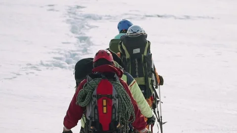 A solid team of climbers in the gear goes into the distance through the snow Stock Footage 105874688