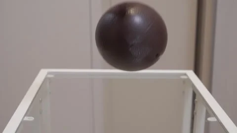 Solid Thud as Hand Drops Dark Brown Textured Ball onto Glass Table Stock Footage 321267543