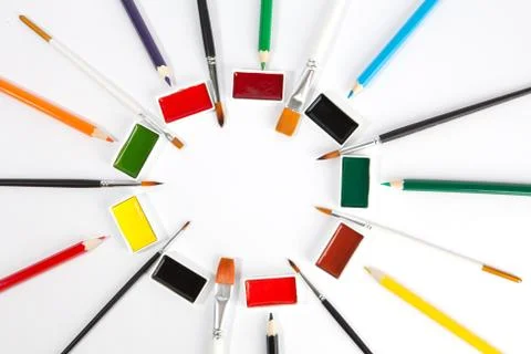 Solid watercolors pans with various paint brushes and colored pencils arrange Stock Photos