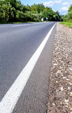 A solid white line marking on an asphalt road in countryside Stock Photos
