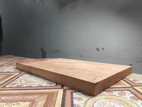 Solid wood cutting board rests against black background Stock-Fotos