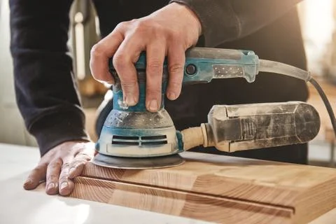 Solid as the wood we work with. Worker grinds the wood of angular grinding Fotos de archivo