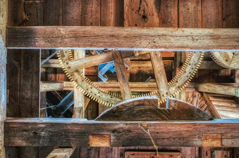 Solid wooden beam supports a cog or gearwheel that drives ancient grindstone Stock Photos