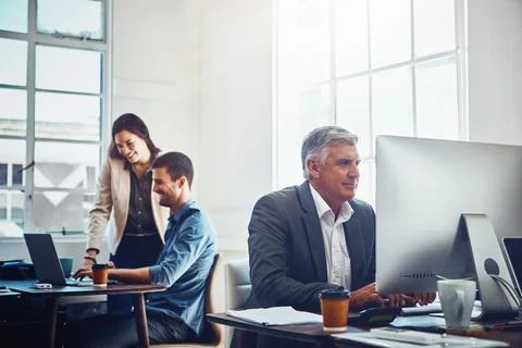 Solid work from a solid team. mature businessman using a computer at work with Stock Photos