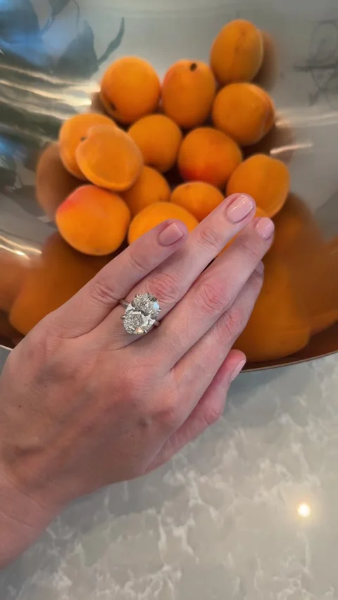 Solitaire ring with oval diamond on hand above apricots vertical video Stock Footage 317021957