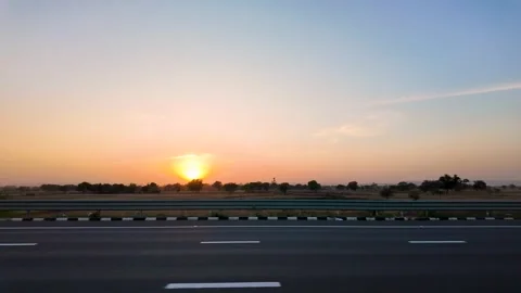 A solitary tree is illuminated by the setting sun on the horizon. Stock Footage 333685219