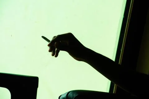 Solitude in Shadows: Hand with Cigarette Foto stock
