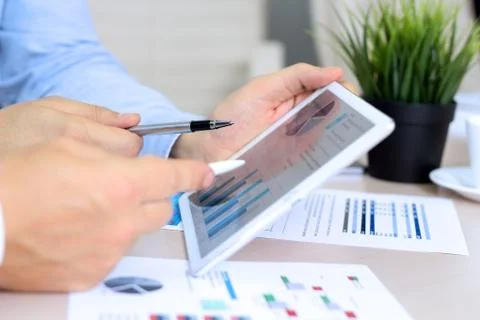 Сolleagues working and analyzing financial figures / graphs on a digital tablet Stock Photos