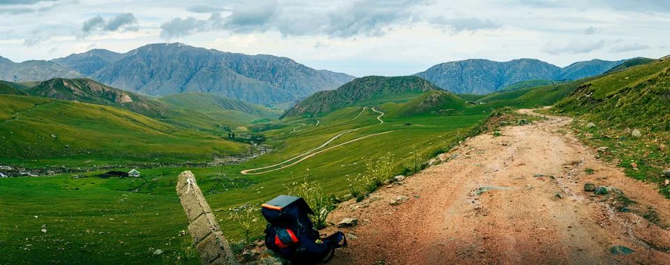 Solo backpacker pause on trail surrounded by lush valleys. Kyrgyzstan Foto stock