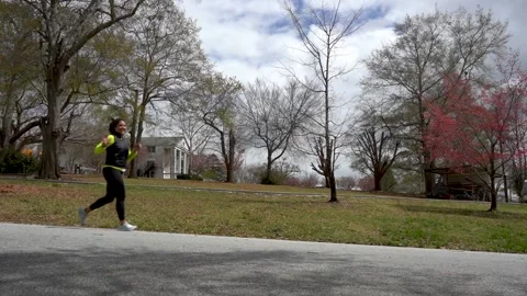 Solo female runner waves to camera with park in background Vidéo 194401210