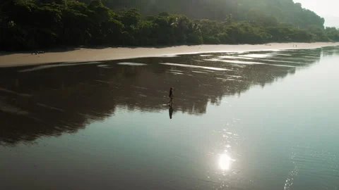 Solo figure walking on glowing reflective Playa Hermosa beach during Costa Rica Stock Footage 345689424