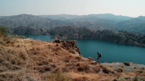Solo hiker with backpack walks along a narrow, dry, rocky ridge Stock Footage 345669265