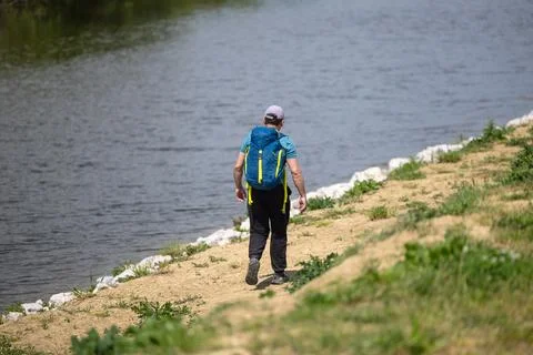 Solo Hiker With Blue Backpack Walking Along Lake Shore On A Sunny Day Stock Photos