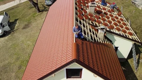 Solo worker using nail gun to place tiles along top edge of roof, aerial Stock Footage 255093627