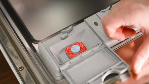 A soluble dishwasher tablet is placed in a special compartment in the dishwasher Stock Footage 324517997