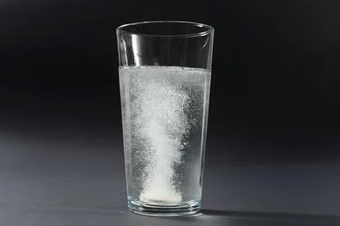 Soluble pill tablet in water with bubbles on black contrasty background Фото