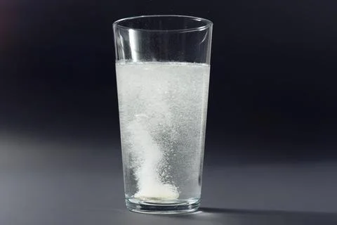 Soluble pill tablet in water with bubbles on black contrasty background Фото