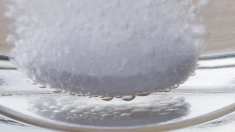 A soluble tablet is dissolving in water. Macro shot Stock Footage 303799475