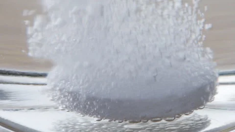 A soluble tablet is dissolving in water. Macro shot Stock Footage 309978511