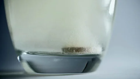 A soluble tablet is dropping into a glass of water to be used as medicine. Stock Footage 128120147
